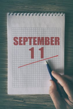 11 Eylül 'de. Ayın 11 'inde insan elini kırmızı altı çizili not defteriyle kapat. Sonbahar ayı, yılın günü konsepti..
