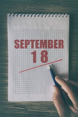 18 Eylül 'de. Ayın 18 'inde insan elini kırmızı altı çizili not defteriyle kapat. Sonbahar ayı, yılın günü konsepti..