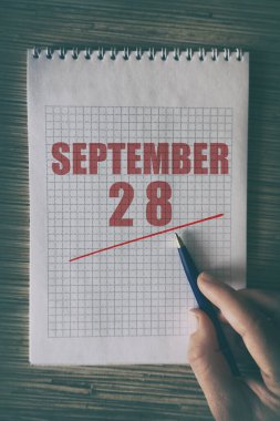 28 Eylül 'de. Ayın 28 'inde insan elini kırmızı altı çizili not defteriyle kapat. Sonbahar ayı, yılın günü konsepti..