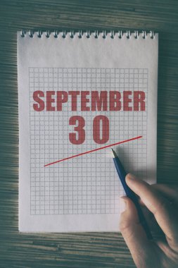 30 Eylül 'de. Ayın 30 'unda insan elini kırmızı altı çizili not defteriyle kapat. Sonbahar ayı, yılın günü konsepti..
