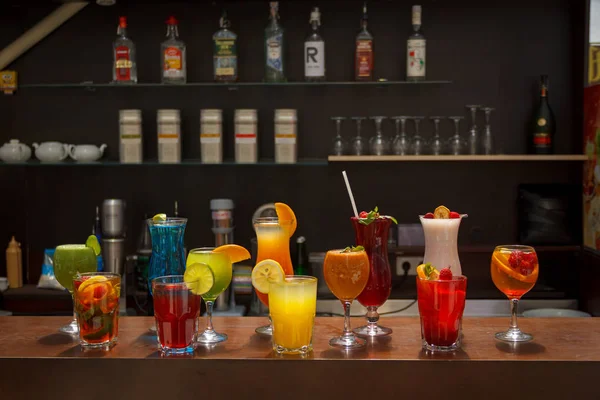 Fresh juices and fruit cocktails on a bar desk. Frontal position. Background brown. General view.