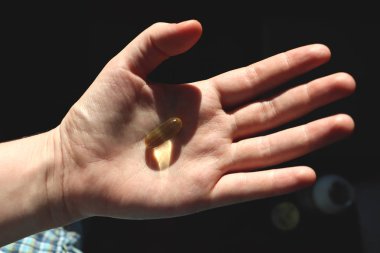 D vitamini veya omega 3 kapsülleri. Vitamini jel el karşı pencere. Vücutta D vitamini eksikliği kavramı