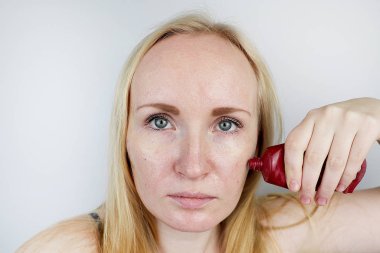 Genç bir kadın bir jel maske yüzünde koyar. Bakım sorun lekeler