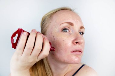 Genç bir kadın bir jel maske yüzünde koyar. Bakım sorun lekeler