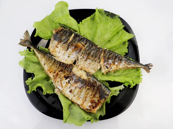 Mackerel is roasted on an electric grill. Grilled fish with lemon and salad