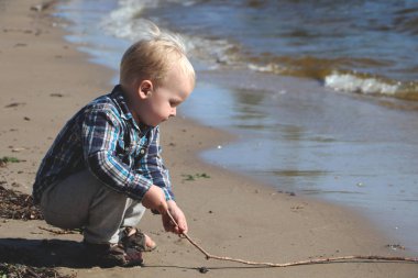 Küçük çocuk kumsalda oynuyor.