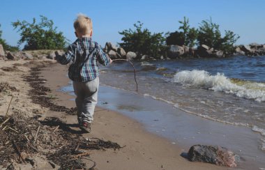 Küçük çocuk kumsalda oynuyor.