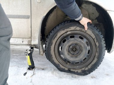 Delikli ve düz lastik yolda. Tekerlek bir jack ile sürücü tarafından yerine