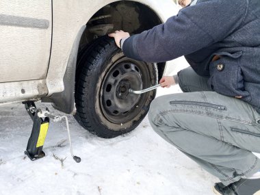 Delikli ve düz lastik yolda. Tekerlek bir jack ile sürücü tarafından yerine