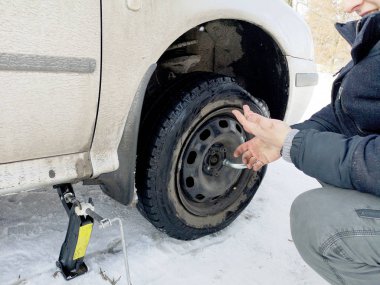 Delikli ve düz lastik yolda. Tekerlek bir jack ile sürücü tarafından yerine