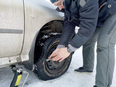 Delikli ve düz lastik yolda. Tekerlek bir jack ile sürücü tarafından yerine