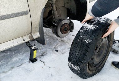 Delikli ve düz lastik yolda. Tekerlek bir jack ile sürücü tarafından yerine