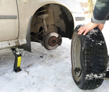 Delikli ve düz lastik yolda. Tekerlek bir jack ile sürücü tarafından yerine