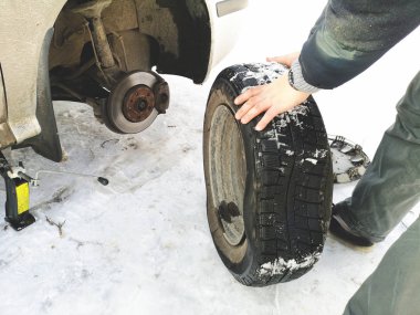 Delikli ve düz lastik yolda. Tekerlek bir jack ile sürücü tarafından yerine