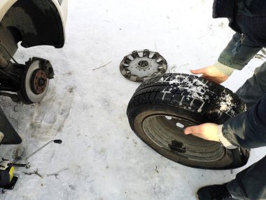 Delikli ve düz lastik yolda. Tekerlek bir jack ile sürücü tarafından yerine