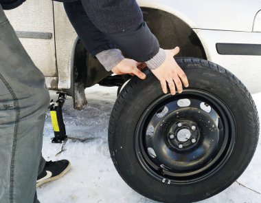 Delikli ve düz lastik yolda. Tekerlek bir jack ile sürücü tarafından yerine