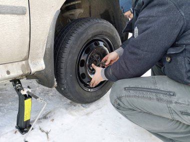 Delikli ve düz lastik yolda. Tekerlek bir jack ile sürücü tarafından yerine