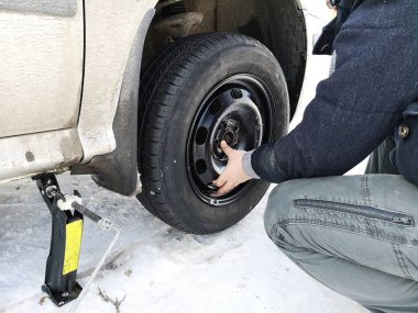 Delikli ve düz lastik yolda. Tekerlek bir jack ile sürücü tarafından yerine