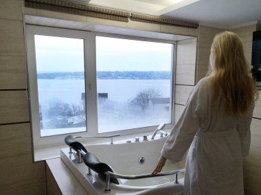 Sıcak bir küvet içinde güzel bir kadın. Otel, panoramik banyo penceresinden jakuzide
