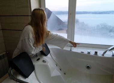 Sıcak bir küvet içinde güzel bir kadın. Otel, panoramik banyo penceresinden jakuzide
