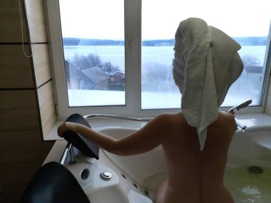 Sıcak bir küvet içinde güzel bir kadın. Otel, panoramik banyo penceresinden jakuzide
