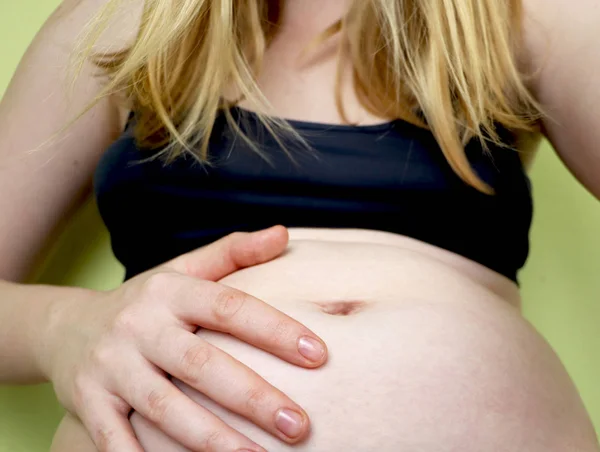 Young pregnant woman, in pain with labor contraction, sitting on bed in bedroom, preparing to give a birth