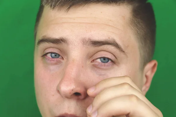 Tears in eyes of crying adult man. Green background. Chromakey