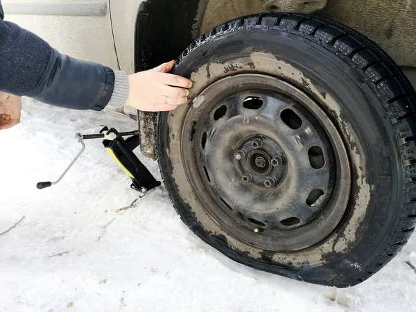 Delikli ve düz lastik yolda. Tekerlek bir jack ile sürücü tarafından yerine