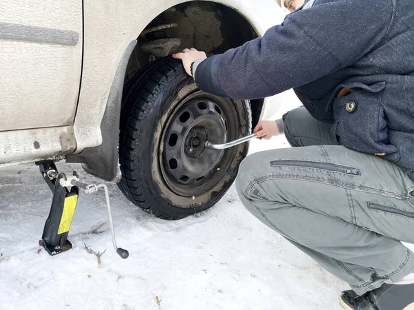 Delikli ve düz lastik yolda. Tekerlek bir jack ile sürücü tarafından yerine
