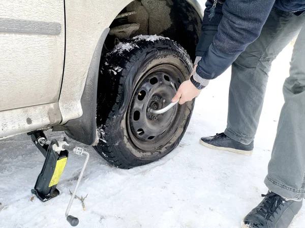 Punched and flat tire on the road. Replacing the wheel with a jack by the driver