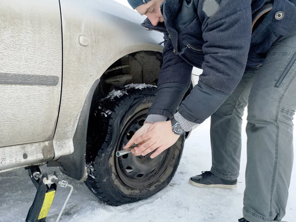 Delikli ve düz lastik yolda. Tekerlek bir jack ile sürücü tarafından yerine
