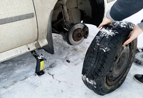 Delikli ve düz lastik yolda. Tekerlek bir jack ile sürücü tarafından yerine