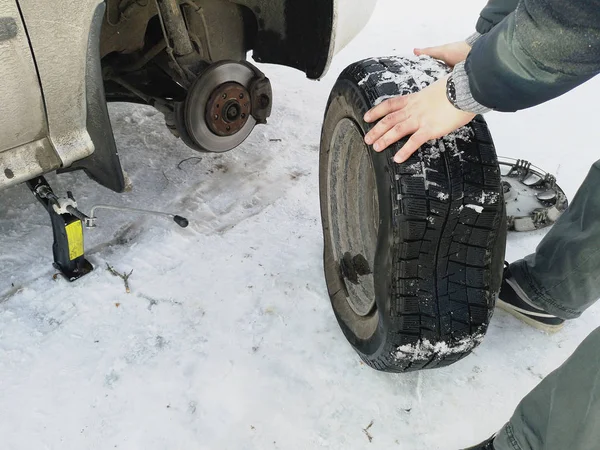 Delikli ve düz lastik yolda. Tekerlek bir jack ile sürücü tarafından yerine