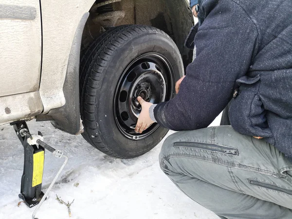 Delikli ve düz lastik yolda. Tekerlek bir jack ile sürücü tarafından yerine