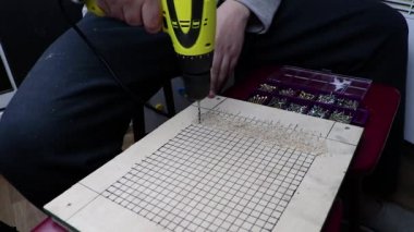 Bir adam delik kontrplak bir matkap ile girer. Ahşap ve el işçiliği ile çalışma kavramı. Video bir çalışma matkap sesi var.