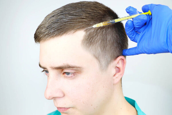 Мезотерапия волос или трансплантация волос: врач-косметолог делает инъекции в голову человека для роста волос или для предотвращения облысения
