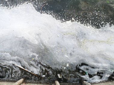 Kumlu sahilde plastik şişeler ve bardaklar. Zllichny çöpyüzer kirli su. Sahilde beyaz köpük