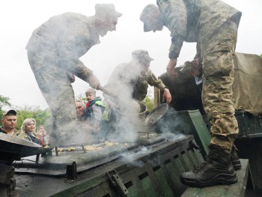 Nikopol, Ukrayna - Mayıs, 2019: Ukraynalı askeri aşçılar askerlerin lapa ve Zafer Günü onuruna geçit töreninde insanlara davranır.