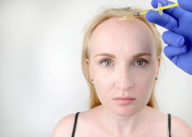 Saç mezoterapisi veya saç nakli: bir güzellik doktoru saç büyüme veya kellik önlemek için bir kadının kafasına enjeksiyonlar yapar