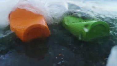 Şişede plastik bardaklar ve tüpler var. Canlı makro fotoğraf plastik. Perspektif, sanki sudan görünüm. Ekoloji ve çevre koruma kavramı