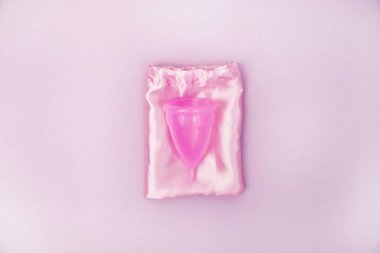 Bir kadın elinde pembe bir arka plan üzerinde bir adet fincan tutar. Kadın sağlığı, hijyen, alternatif ped ve tampon kavramı