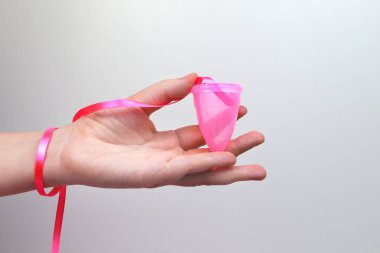 Bir kadın elinde pembe bir arka plan üzerinde bir adet fincan tutar. Kadın sağlığı, hijyen, alternatif ped ve tampon kavramı