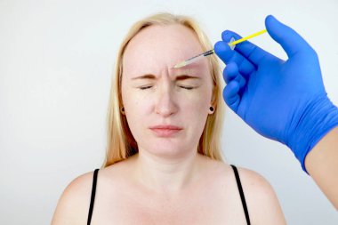 Alnında botoks enjeksiyonu, dikey kırışıklık kaldırın. Güzellik uzmanında resepsiyonda genç kadın, gençleşme prosedürü