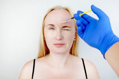 Alnında botoks enjeksiyonu, dikey kırışıklık kaldırın. Güzellik uzmanında resepsiyonda genç kadın, gençleşme prosedürü