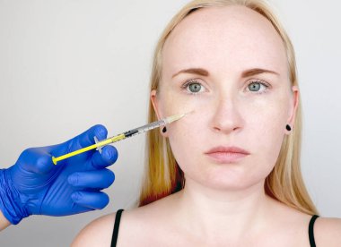 Bir Kozmetolog bir prosedür gerçekleştirir-genç bir kadının yüzüne bir enjeksiyon. Güzellik enjeksiyonları, mezoterapi, hyaluronik asit enjeksiyonları, biorevitalization, yanak düzeltme, dolgu maddeleri