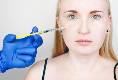 Bir Kozmetolog bir prosedür gerçekleştirir-genç bir kadının yüzüne bir enjeksiyon. Güzellik enjeksiyonları, mezoterapi, hyaluronik asit enjeksiyonları, biorevitalization, yanak düzeltme, dolgu maddeleri