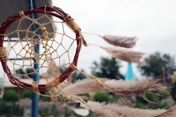 Dream catchers develop in the wind against the backdrop of the beach. A lot of space in the frame creates a feeling of calm and serenity, and developing dream catchers create a sense of security.