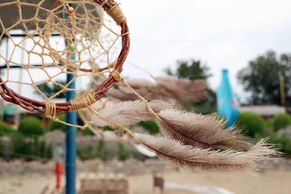 Dream catchers develop in the wind against the backdrop of the beach. A lot of space in the frame creates a feeling of calm and serenity, and developing dream catchers create a sense of security.