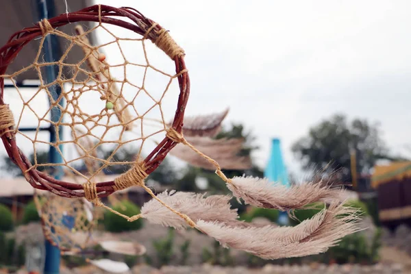 Dream catchers develop in the wind against the backdrop of the beach. A lot of space in the frame creates a feeling of calm and serenity, and developing dream catchers create a sense of security.