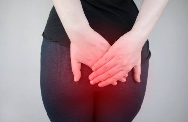 A woman holds his hands to the ass feeling pain. Conversion of pain in the rectum, hemorrhoids and pain in the excretory system of the body. Frequent bowel movements.